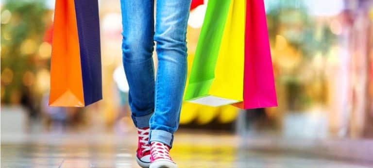 Shopper walking through a mall carrying brightly colored shopping bags