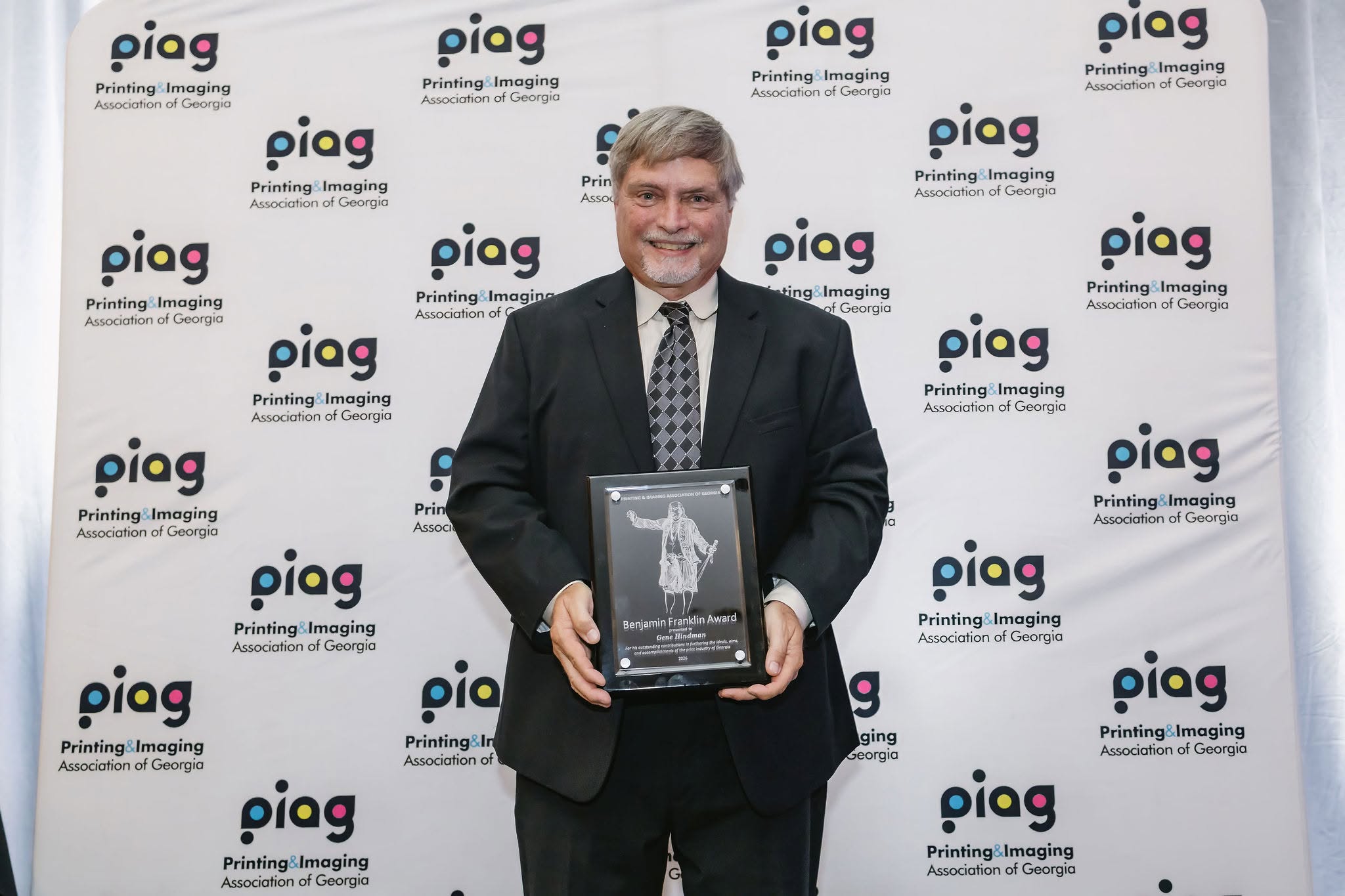 Gene Hindman holding the Printing and Imaging Association of Georgia's Benjamin Franklin Award plaque at the imPRESS 2026 ceremony.